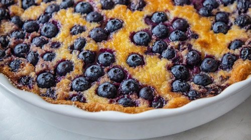close up of blueberry cobbler in a shallow white baking dish