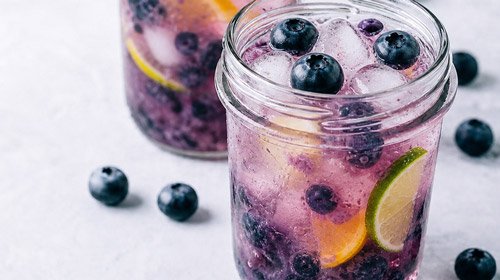 light refreshing looking drink with blueberries and ice in a mason jar glass